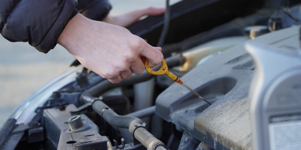 Mechanic refilling engine oil in a car at a service center during routine vehicle maintenance.