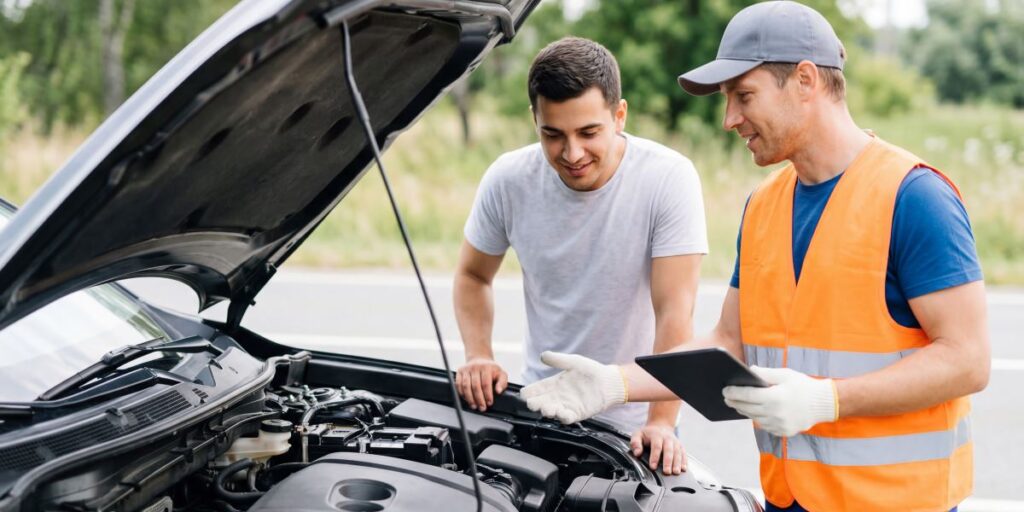 Car mechanic and vehicle owner inspecting a car engine together while discussing maintenance and repair.