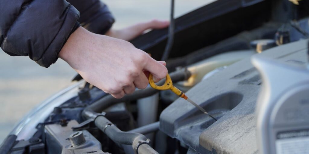 Mechanic refilling engine oil in a car at a service center during routine vehicle maintenance.