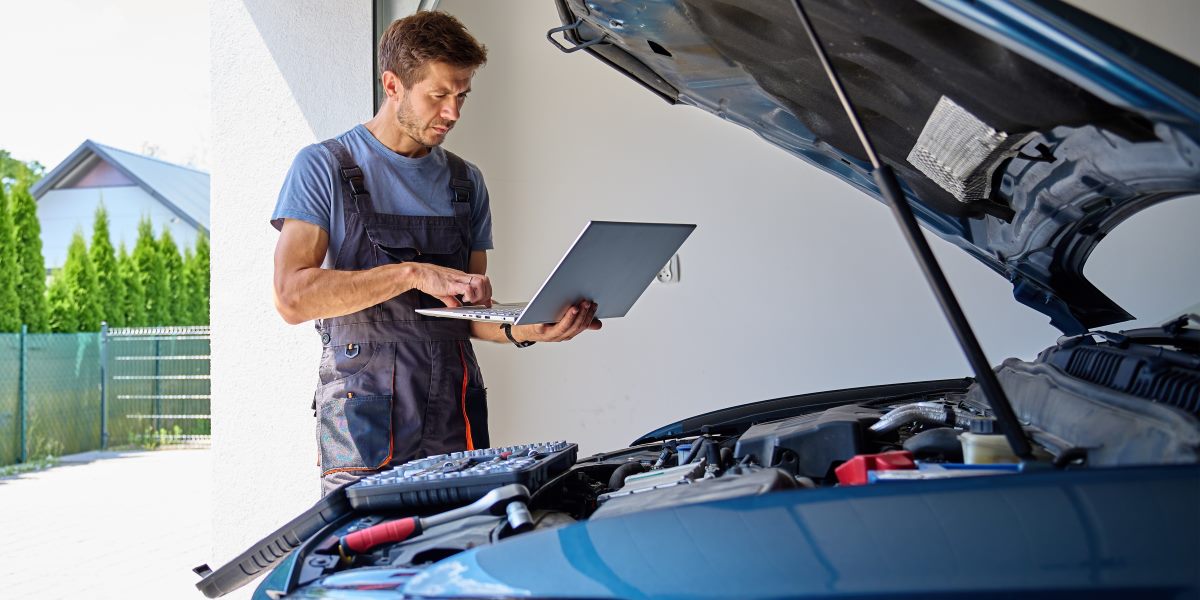 A man learning from his laptop about car maintenance.