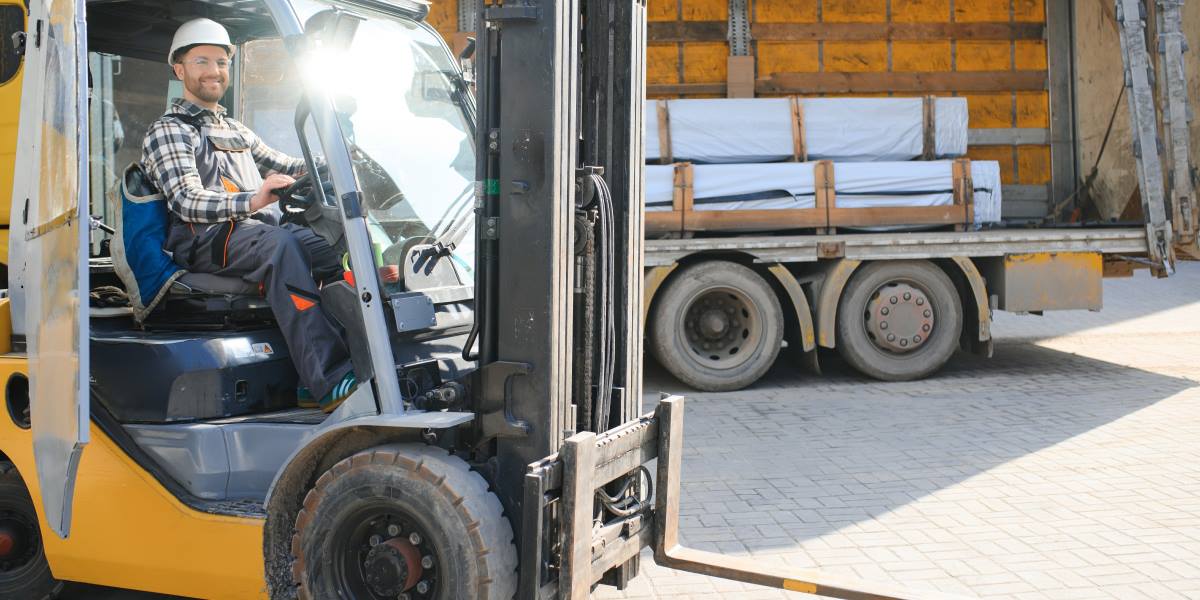 A worker driving a Forklift in a large warehouse.