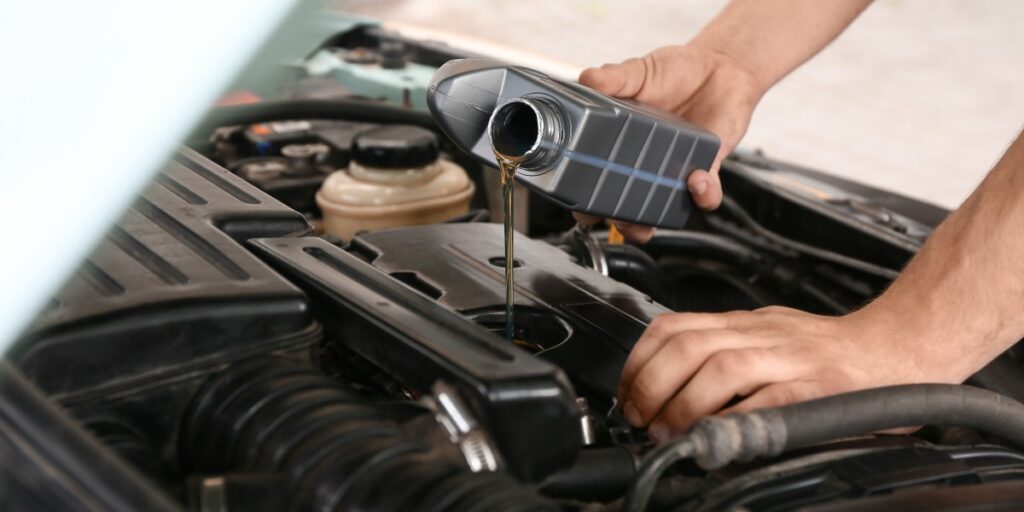 A mechanic is filling up an engine with brand-new engine oil.