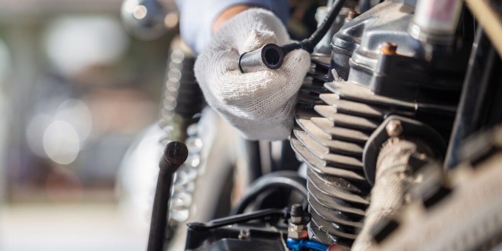 Mechanic removing spark plug from a motorcycle engine.
