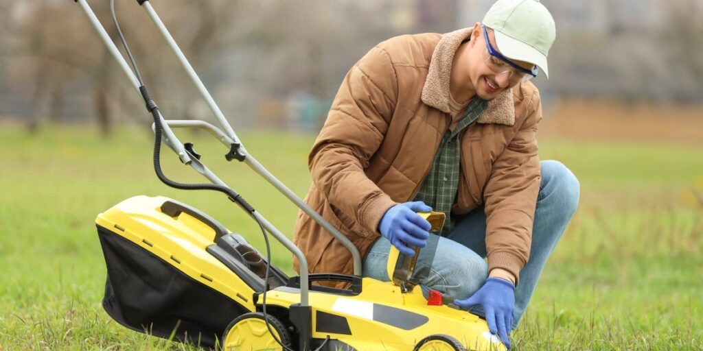 A young man with a lawn mower outside in winter.