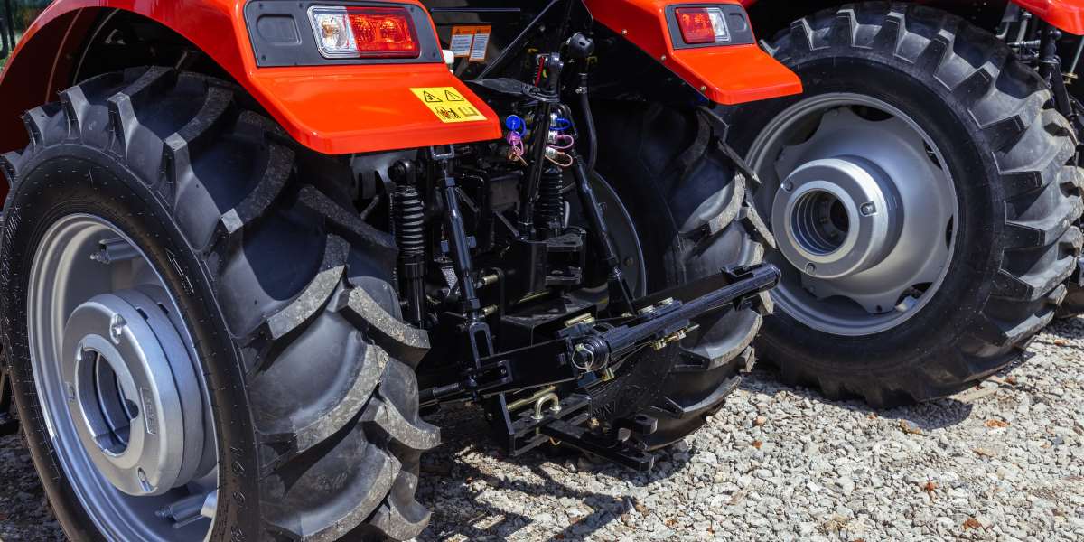 Rear view of a modern agricultural tractor with a hydraulic hitch inside a hangar.