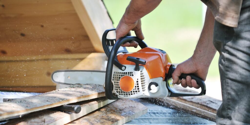 Woodworker using a two-stroke chainsaw to cut wood.